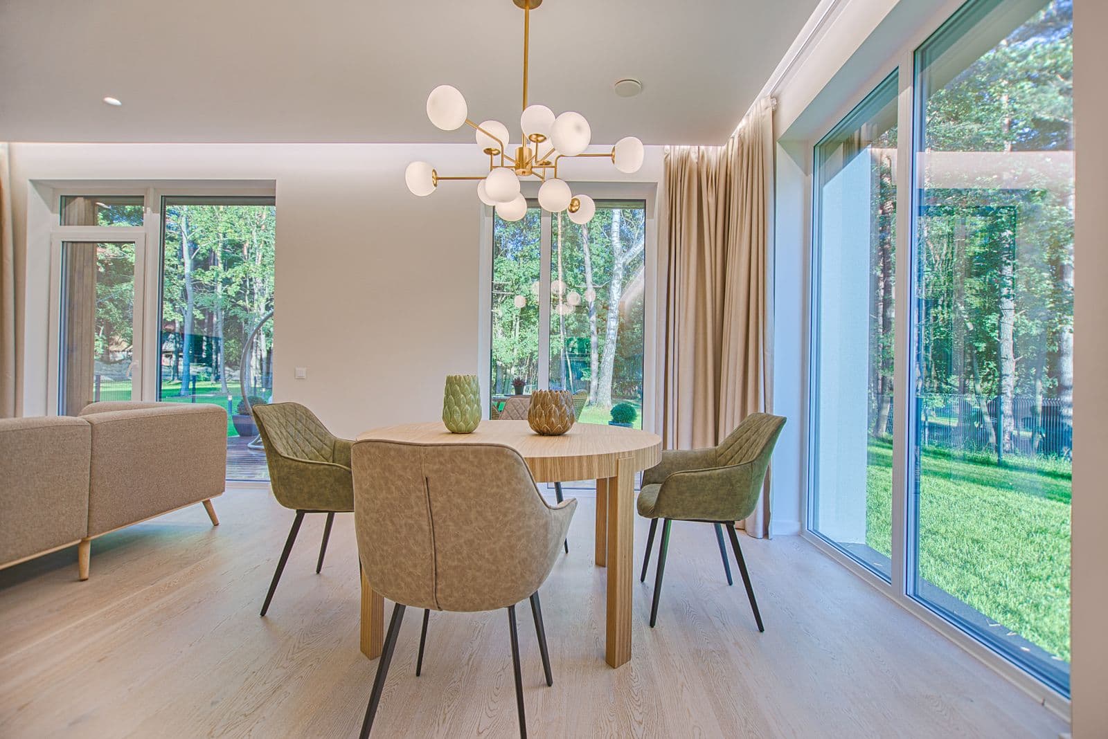 Round dining table by tall windows looking onto trees and a lawn